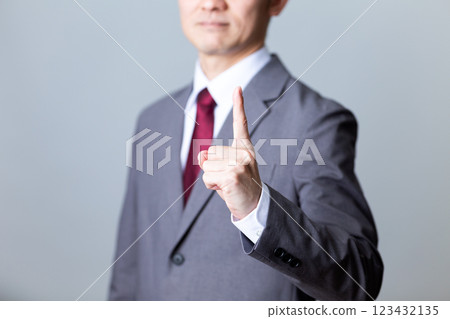 A middle-aged male businessman wearing a gray suit and pointing his index finger 123432135