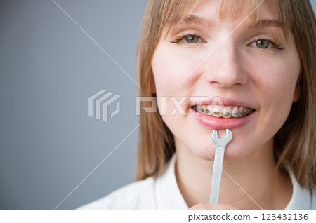 The woman jokingly tightens the wire of the brakes with a wrench. Bite correction device 123432136