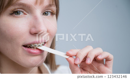 Young woman with metal braces on her teeth is chewing gum. The girl is eating gummy candy 123432146