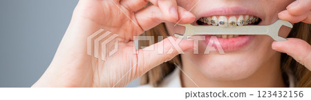 Close-up portrait of a woman with braces holding a wrench in her teeth.  123432156