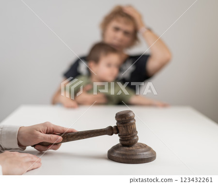 A judge hits a gavel against the backdrop of an elderly woman holding a child.  123432261