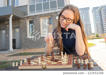 Caucasian woman playing chess outdoors. 123432288