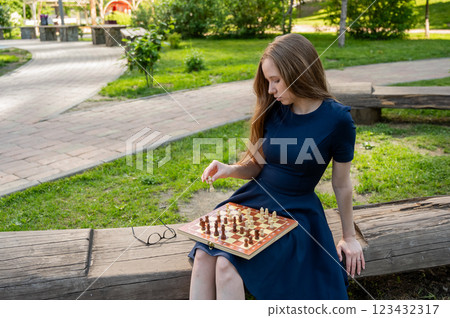 Caucasian woman playing chess outdoors. 123432317