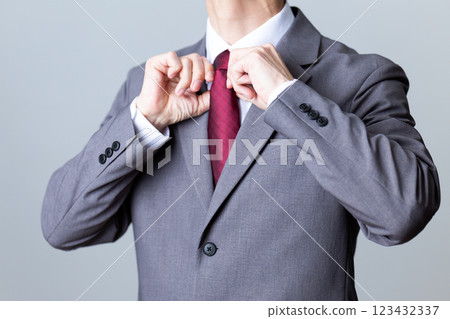A middle-aged male businessman wearing a gray suit and fixing his tie A middle-aged male businessman wearing a gray suit and fixing his tie 123432337