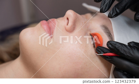 Caucasian woman undergoing eyelash lamination procedure.  123432379