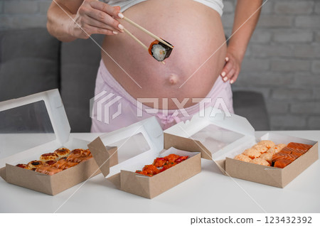 A pregnant woman stands at a table with rolls. Close-up of the belly. A pregnant woman stands at a table with rolls. Close-up of the belly. 123432392