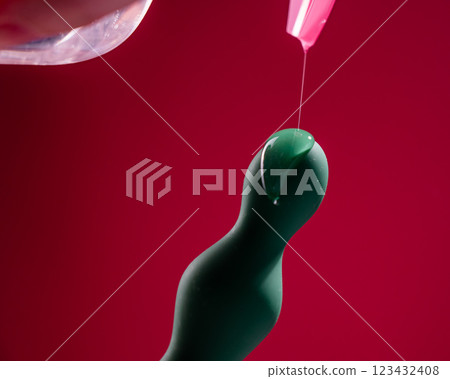 Lube pouring onto green anal beads on pink background. Lube pouring onto green anal beads on pink background. 123432408