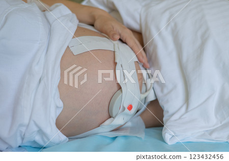 Close-up of pregnant woman's belly with Cardiotocography sensor in delivery room of maternity home. 123432456