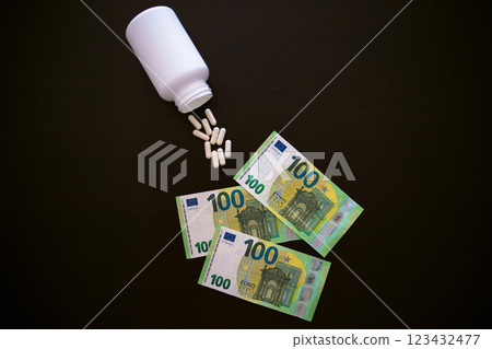 A jar of tablets on a black table. 100 euros in paper banknotes. 123432477