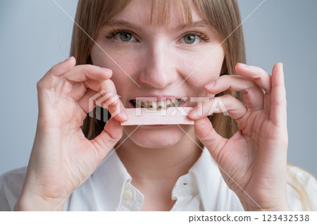 Young woman with metal braces on her teeth is chewing gum. The girl is eating gummy candy Young woman with metal braces on her teeth is chewing gum. The girl is eating gummy candy 123432538