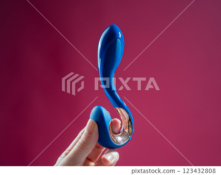 Lube pouring onto blue sex toy on pink background.  123432808