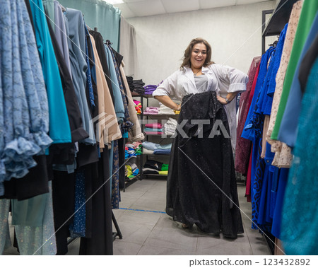 A fat woman chooses clothes in a plus size store.  123432892