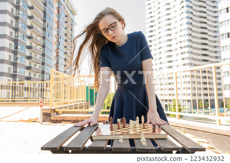 Caucasian woman playing chess outdoors. 123432932