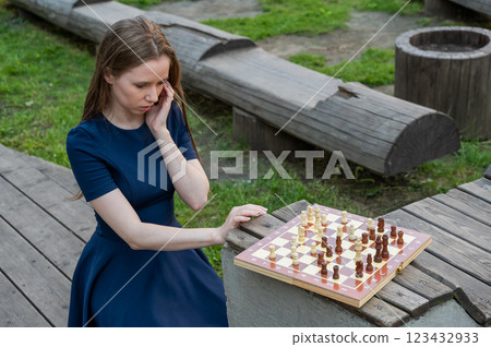 Caucasian woman playing chess outdoors. Caucasian woman playing chess outdoors. 123432933
