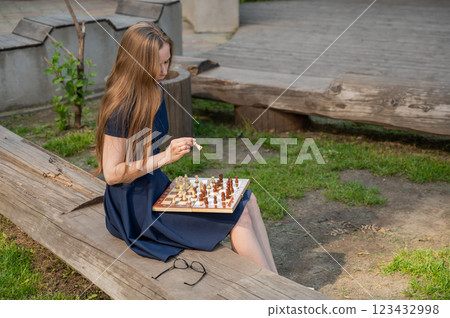 Caucasian woman playing chess outdoors. Caucasian woman playing chess outdoors. 123432998