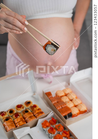 A pregnant woman stands at a table with rolls. Close-up of the belly. 123433057