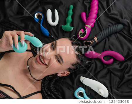Portrait of Caucasian woman lying on bed among sex toys.  123433058