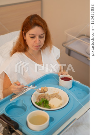 Caucasian woman eating on hospital bed.  123433088