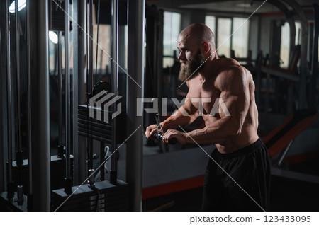Bald Caucasian Bodybuilder doing heavy triceps exercises with cable. Bald Caucasian Bodybuilder doing heavy triceps exercises with cable. 123433095