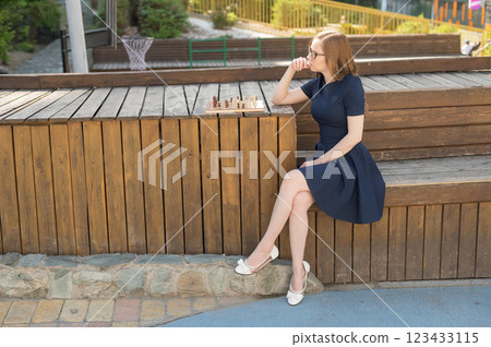 Caucasian woman playing chess outdoors. 123433115