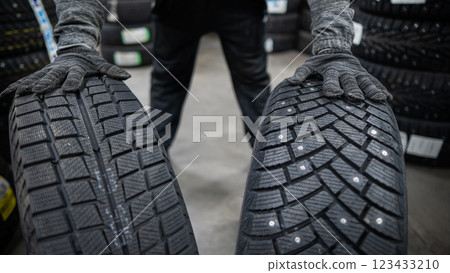 Mechanic keeps new summer and winter car tires in the garage. Comparison of wheels for different seasons.  123433210