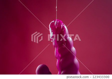 Lube pouring on pink dildo on pink background. Lube pouring on pink dildo on pink background. 123433300
