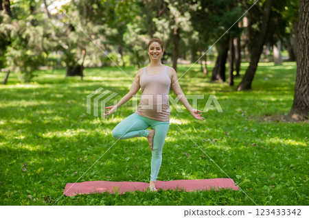 Pregnant caucasian woman doing yoga in the park. Tree pose. Pregnant caucasian woman doing yoga in the park. Tree pose. 123433342