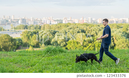 Man running with pit bull terrier outdoors.  123433376