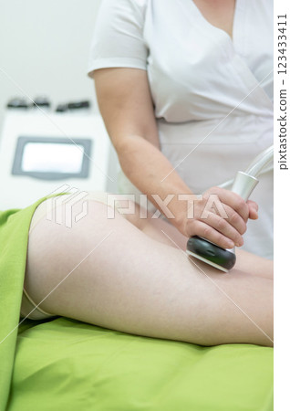 Caucasian woman on hardware anti-cellulite massage. Thigh cavitation procedure. 123433411