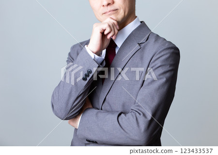 一位身穿灰色西裝、憂心忡忡的中年男性商人 一位身穿灰色西裝、憂心忡忡的中年男性商人 123433537