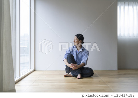 A man in his 40s sitting on a wooden floor 123434192