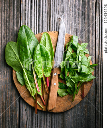 Slicing green sorrel leaves on a rustic wooden cutting board Slicing green sorrel leaves on a rustic wooden cutting board 123434298