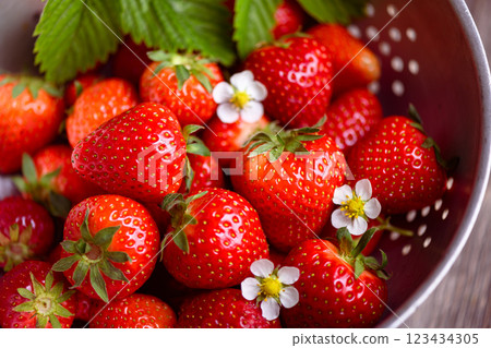 Ripe red strawberry surrounded by green leaves 123434305