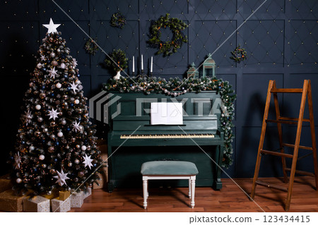 green piano blue wall decorated with christmas tree decor. classic christmas photo zone with piano 123434415