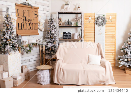 sofa with knitted light blanket new year trees and poster. new year family photo zone with furniture 123434440