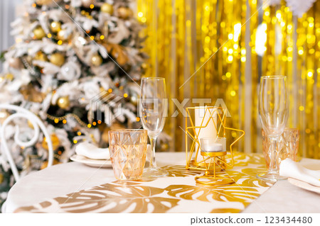 New Year's table setting in a photo studio. Plates with glasses on a Christmas tablecloth 123434480
