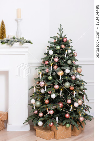 Christmas tree with white and pink toys on a light wall. New Year's decoration in a photo studio Christmas tree with white and pink toys on a light wall. New Year's decoration in a photo studio 123434499