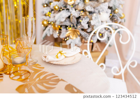 New Year's table setting in a photo studio. Plates with glasses on a Christmas tablecloth New Year's table setting in a photo studio. Plates with glasses on a Christmas tablecloth 123434512