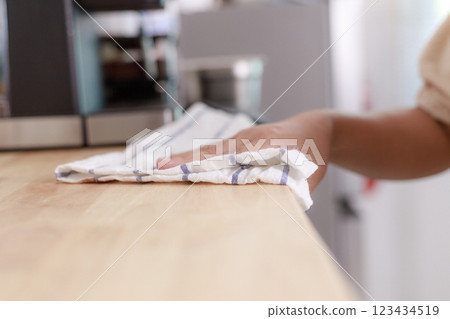 Hands of the woman uses fabric and water spray to clean the wooden table 123434519