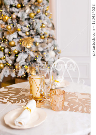 New Year's table setting in a photo studio. Plates with glasses on a Christmas tablecloth 123434528