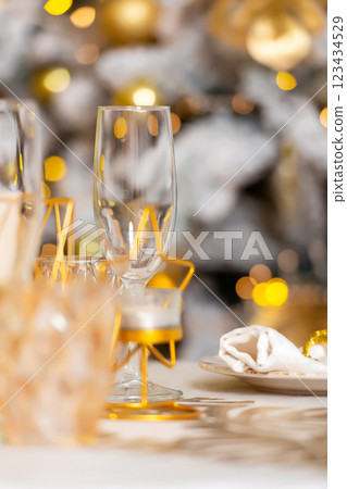 New Year's table setting in a photo studio. Plates with glasses on a Christmas tablecloth 123434529