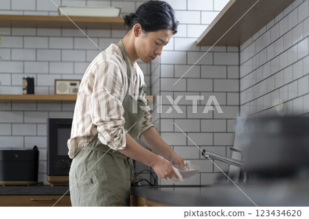 一名 40 多歲的男子在廚房洗碗，側面 123434620