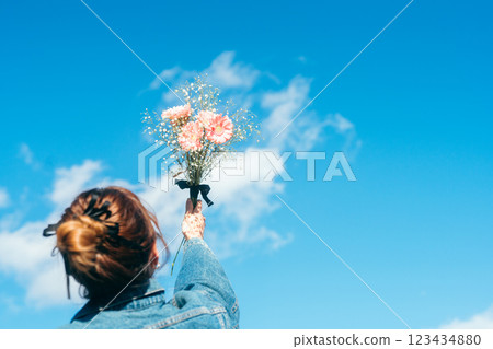 一位女士手持一束粉紅色花的背影 123434880