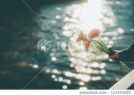 波光粼粼的水面和手中的粉紅色花束電影風格 123434889