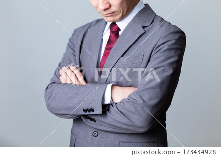 A middle-aged male businessman wearing a gray suit and worried 123434928