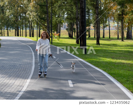 Caucasian woman roller skating with her jack russell terrier dog in park.  123435062