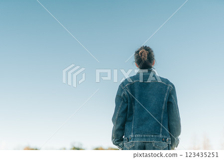 Back view of a woman looking up at the hazy blue sky in the evening 123435251