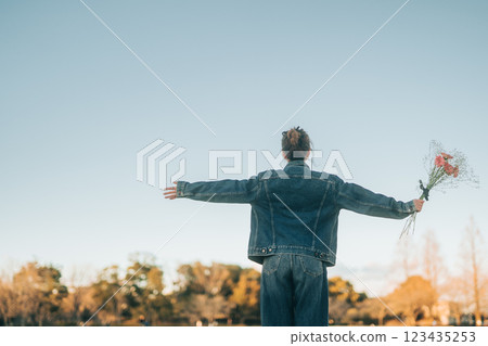 一位女士的背影，張開雙手，仰望傍晚朦朧的藍天 123435253