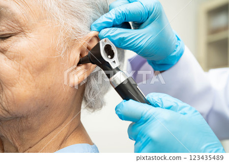 Otolaryngologist or ENT physician doctor examining senior patient ear with otoscope, hearing loss problem. Otolaryngologist or ENT physician doctor examining senior patient ear with otoscope, hearing loss problem. 123435489