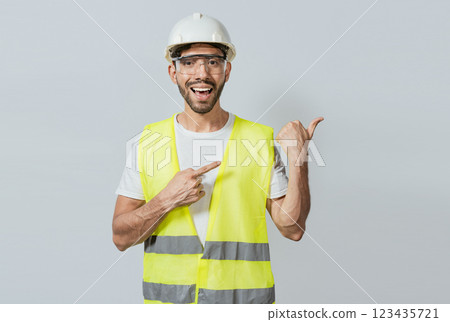 Construction engineer with vest pointing at an advertisement. Engineer man pointing to side. Builder engineer pointing finger to the right isolated, Portrait of engineer man pointing aside Construction engineer with vest pointing at an advertisement. Engineer man pointing to side. Builder engineer pointing finger to the right isolated, Portrait of engineer man pointing aside 123435721
